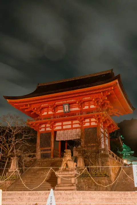 A vermilion shrine building illuminated against a dark evening sky