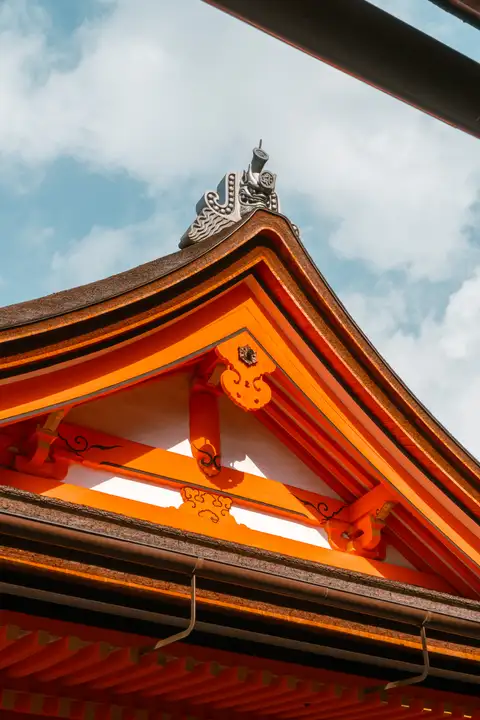 Sunlight catching the orange wooden eaves of a shrine against a blue sky