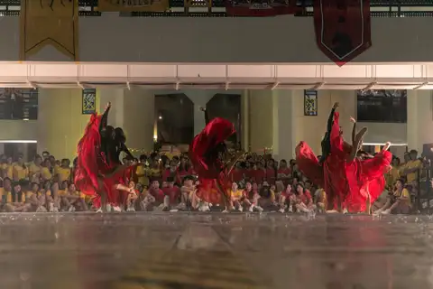 Dancers lifting red fabric during a courtyard performance before a crowd