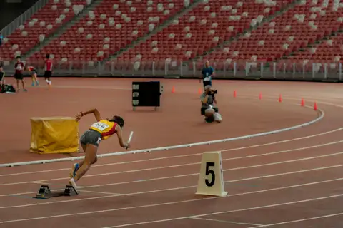 A Hwa Chong relay runner driving forward from the starting blocks with a baton